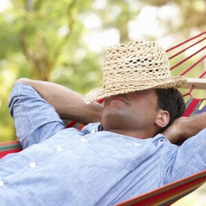 farmer relaxing in a hamick with a hat over his eyes